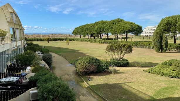 Zona residencial con un camino, césped verde y árboles.