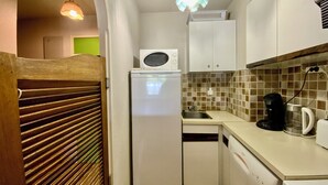 Cocina compacta equipada con refrigerador, microondas, lavabo y cafetera.
