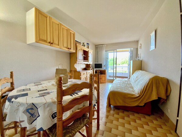 Une pièce avec un lit, une table sur laquelle repose un journal, des meubles en bois et un téléviseur.