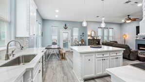 Una cocina moderna con armarios blancos, una isla central y una zona de comedor con banco.
