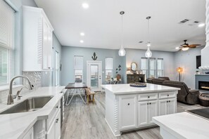Une cuisine moderne avec des meubles blancs, un îlot central et un coin repas avec une banquette.