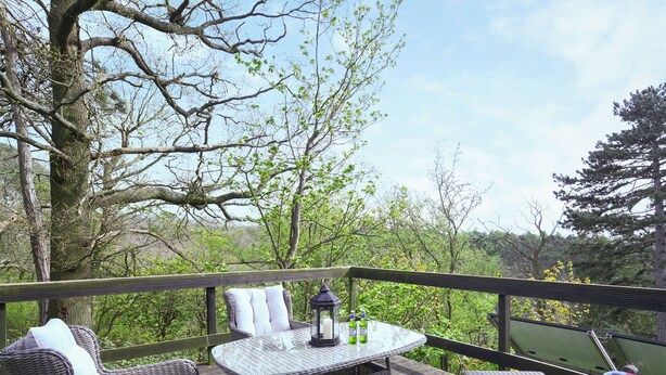 Een terras met rieten meubels, een glazen tafel en een lantaarn.