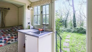 Een compacte keuken met een spoelbak, een raam en een deur naar een tuin.