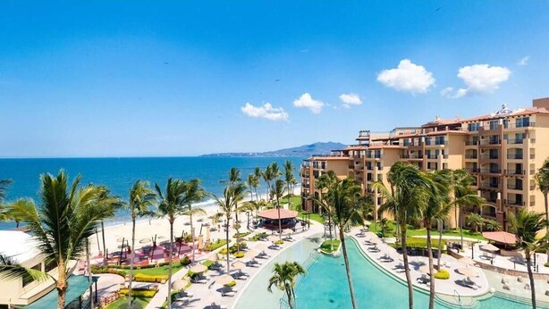 A resort with a pool, palm trees, and a view of the ocean. - Affordable Luxury In Mexico 1 (Nuevo Vallarta)