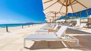 A beachside hotel with sun loungers and umbrellas, a clear blue sky, and a calm sea. - Affordable Luxury In Mexico 1 (Nuevo Vallarta)