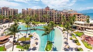 A resort with a large pool, palm trees, and a view of the ocean.