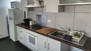 Een moderne keuken met witte kastjes, een roestvrijstalen afzuigkap, een magnetron en een spoelbak.