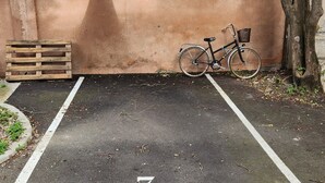 Een parkeerplaats met een fiets, een houten pallet en een boom.