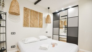 Una camera da letto moderna con un letto grande, un armadio con specchio e due lampade a sospensione.