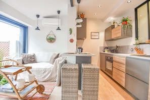 A modern kitchen with a central island, built-in appliances, and a hanging light fixture. - La Terrasse Ricard - Belle maison 1 ch avec clim (Marseille)