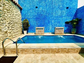 Ein Schwimmbecken mit einer Steinmauer und blauem Mosaik.