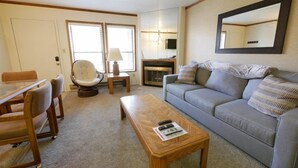 Ein gemütliches Wohnzimmer mit einer Couch, einem Esstisch mit Stühlen, einem kleinen Beistelltisch und einer Lampe.