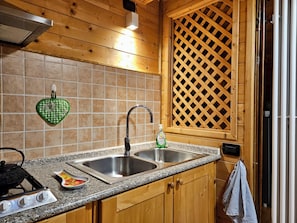 Una cocina con encimeras de granito, pileta de acero inoxidable, armarios de madera y un toallero con forma de corazón a cuadros.