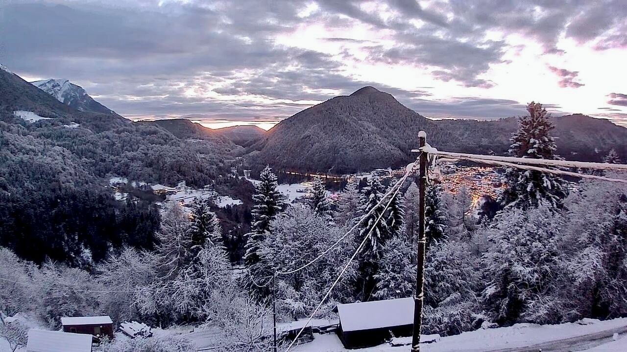 Een bergachtig landschap met sneeuwbedekte bomen en een heldere lucht.