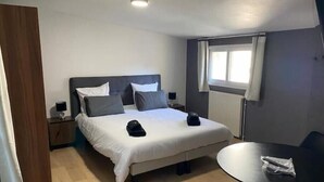 Quarto de hotel com cama, mesas de cabeceira, uma pequena mesa e uma janela.