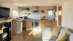 Une cuisine moderne avec des meubles en bois, un four à micro-ondes encastré et une cuisinière à gaz.