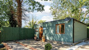 Une petite cabane à un seul étage, dotée d’une porte d’entrée, d’une fenêtre et d’un petit porche.