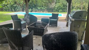An outdoor patio with wicker furniture, a barbecue grill, and a view of a swimming pool. - Hidden Paradise w/ Pool (Guaynabo)