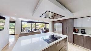 Una cucina moderna con una grande isola, elettrodomestici integrati e vista sull'esterno.