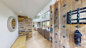 Un interno moderno con una parete in pietra, una porta in legno con ferramenta metallica e vista all'esterno.