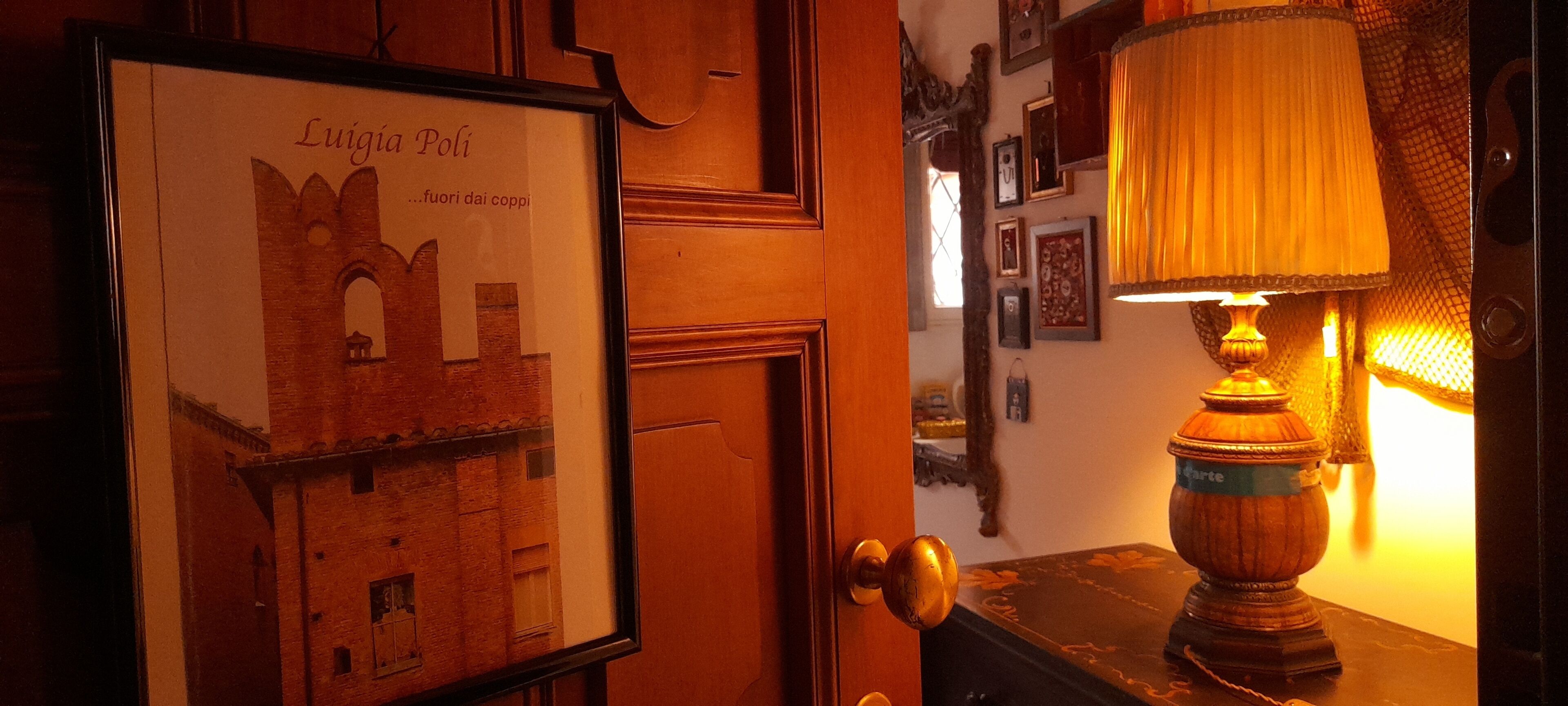 Ein gerahmtes Bild einer Burg an einer Wand, eine Lampe auf einem Tisch und eine Tür mit goldener Klinke.