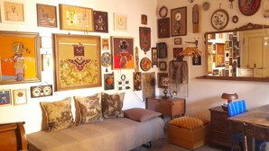 Une pièce comprenant un canapé, une table et divers éléments de décoration murale, notamment des tableaux encadrés et des miroirs.