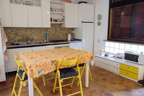 A kitchen with a dining table, chairs, cabinets, a microwave, and a window.