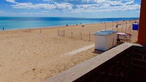 Una playa con cielo despejado, orilla arenosa y algunas personas.