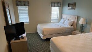 Ein Hotelzimmer mit zwei Betten, einem Fernseher auf einem Beistelltisch und einer Lampe auf dem Nachttisch.
