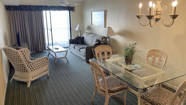 Ein Hotelzimmer mit Essbereich, einer Couch, einem Deckenventilator und einer Kristallleuchter.