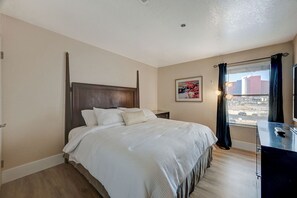 A hotel room with a large bed, a desk with a computer, a window with curtains, and a painting on the wall. - Las Vegas Condo minutes from the Strip, Team Mobile and Allegiant Stadium (Las Vegas)