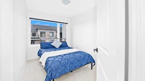 Une chambre à coucher avec un lit, une fenêtre et une vue sur les bâtiments environnants.