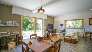 A spacious living area with a wooden dining table, a sofa, and a large window offering a view of the outdoors. - Cozy home in Marsaglia with kitchen (Marsaglia)