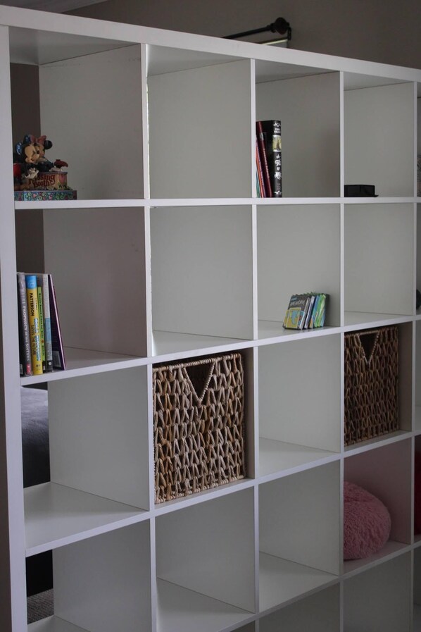 A white bookshelf with multiple shelves, some containing books and decorative items.