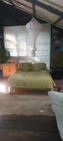 A bed with a green patterned bedspread, a wooden headboard, and a canopy.