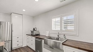 A modern kitchen with white cabinetry, stainless steel appliances, and a wooden countertop. - Seaside Breeze - 4BR 3BA 5 min. Walk to Beach (Kill Devil Hills)