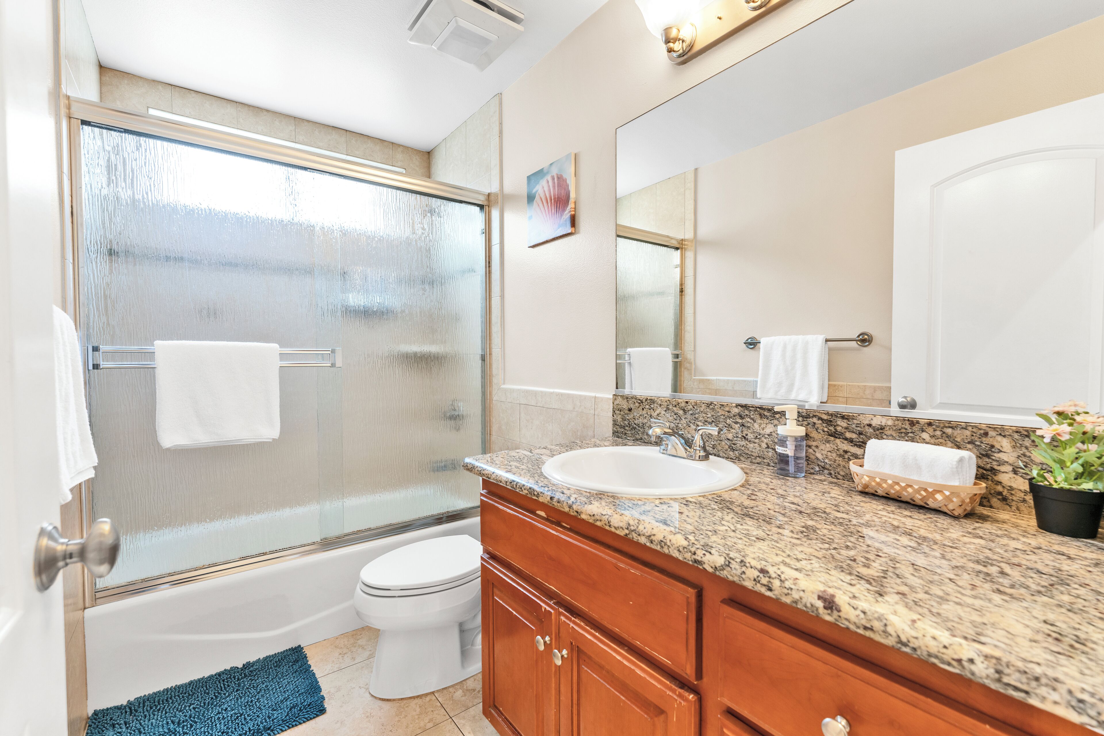 A modern bathroom with a glass shower enclosure, a white sink, and wooden cabinetry.