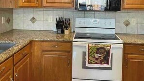 A kitchen with wooden cabinets, a microwave, an oven, and a tiled backsplash. - Hello guests, welcome to our ranch house in a quiet neighborhood. (Urbandale)