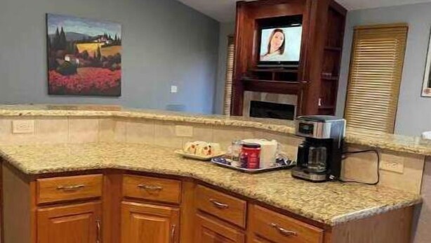 A kitchen with wooden cabinets, a granite countertop, a ceiling fan, and a painting on the wall. - Hello guests, welcome to our ranch house in a quiet neighborhood. (Urbandale)