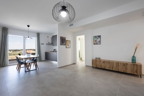 Un intérieur moderne comprenant un coin repas, une cuisine et une grande fenêtre offrant une vue dégagée.