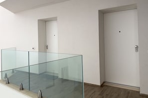 Un intérieur moderne avec une rambarde en verre, une porte et un plancher de couleur claire.