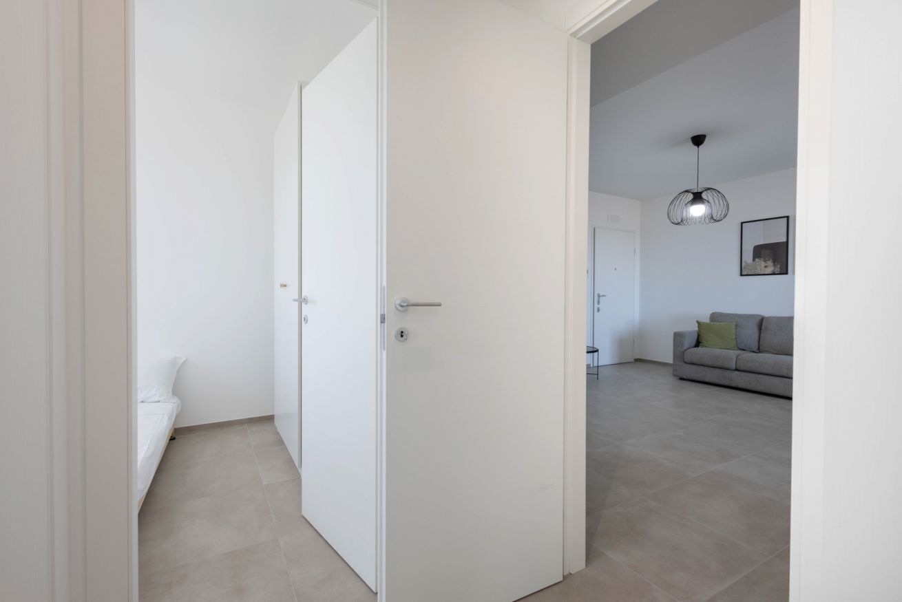 Ein Zimmer mit einer weißen Tür, einem Bett und einer Couch im Hintergrund.