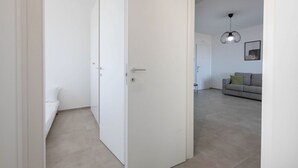 Una habitación con una puerta blanca, una cama y un sofá al fondo.
