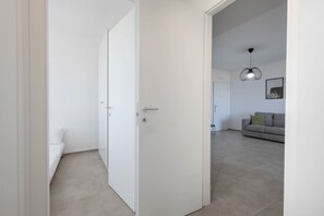 Een kamer met een witte deur, een bed en een bank op de achtergrond.