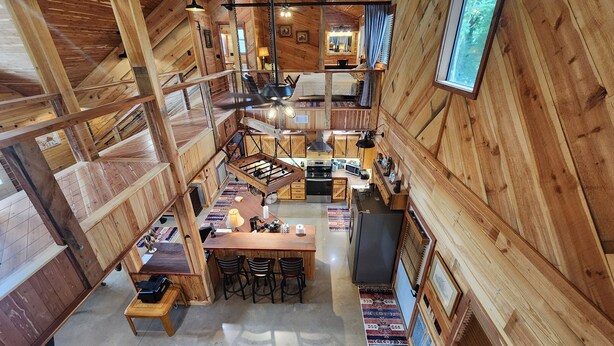 Un vaste espace de vie de style loft, doté d’un plafond haut, de poutres apparentes, d’un espace cuisine central et d’un coin repas avec un bar.