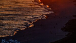 Ein Sonnenuntergang über einem Strand mit einem sich ins Wasser erstreckenden Steg.