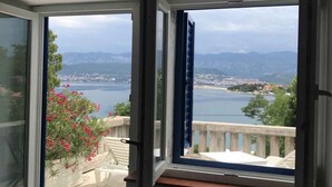 Quarto com uma grande porta de correr de vidro que dá para uma varanda com vista para um lago e montanhas.