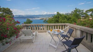 Terraço com mesa posta para dois, com vista para a costa.