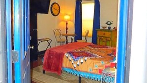 Ein Schlafzimmer mit einem Bett, einem Deckenventilator, einer Uhr, einer Lampe und einem kleinen Tisch.