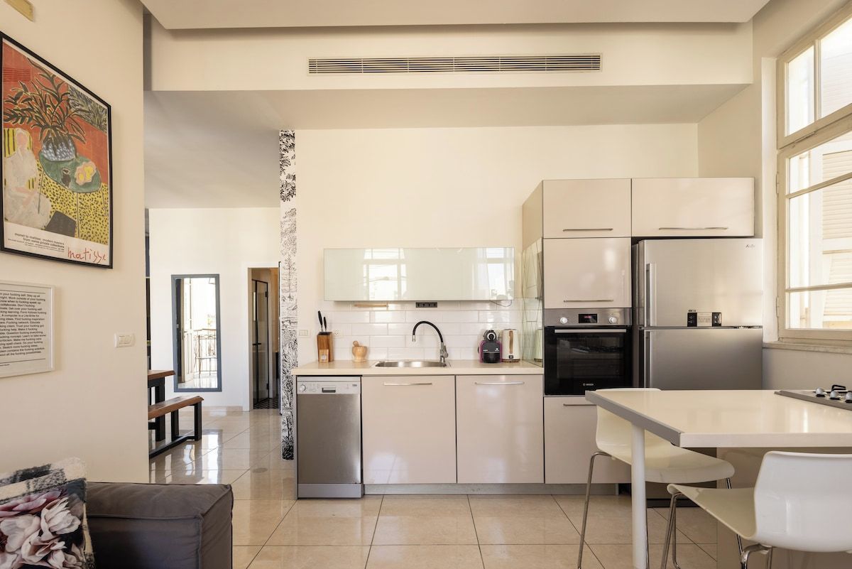Una cocina moderna con armarios blancos, un refrigerador de acero inoxidable y un lavavajillas.